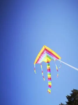 Multicolored kite attached to white string against blue sky Stock Photos