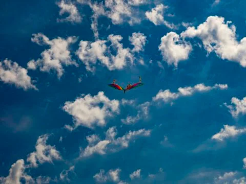 Multicolored kite in the sky between the clouds. Stock Photos