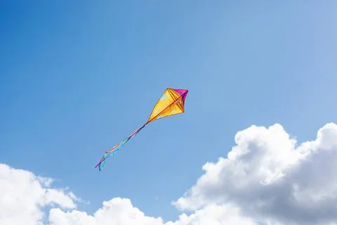 A multicolored kite soars in the sky Stock Photos