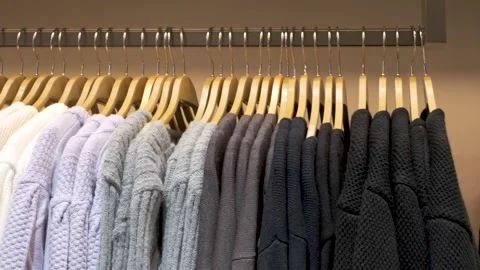 Multicolored knitted sweaters hanging on hangers close up in women's clothing Stock Footage 272845569