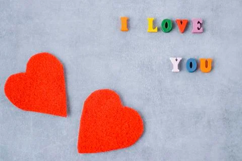 Multicolored letters and two red decorative hearts on gray background. I love Stockfoto's