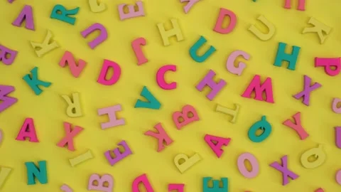 Multicolored letters rotating on yellow background. top view. back to school. 4k Stock Footage 202316371