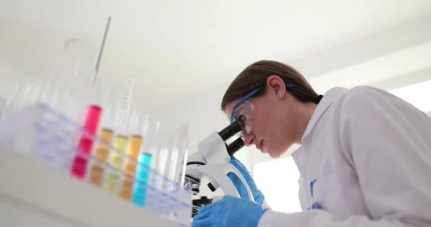 Multicolored liquid in test tubes and female scientist laboratory assistant Stock Footage 255806033