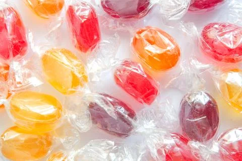 Multicolored lollipops candy in transparent packaging background Stock Photos
