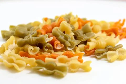 Multicolored macaroni close-ups fall from above on a white background. Fotos Stock