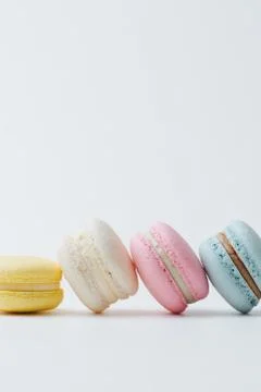 Multicolored macarons arranged in a row with each next cake leaning on the ot Stock Photos