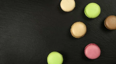 Multicolored macarons on black background with copy space top view Stock Photos