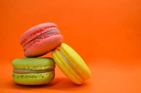 Multicolored macarons on an orange background Stock Photos