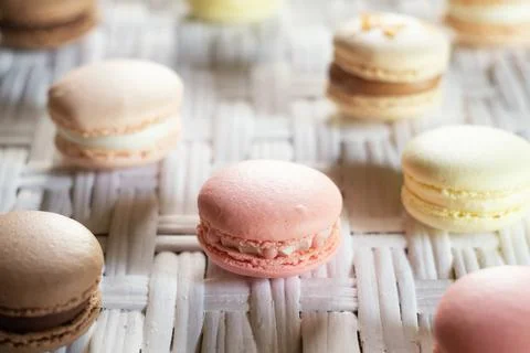 Multicolored macarons on white wicker table Stock Photos