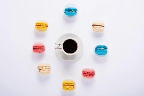 Multicolored macaroon around and coffee on white background from above Fotos Stock