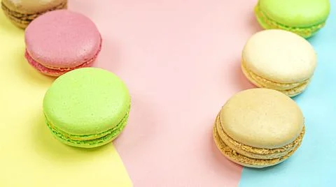 Multicolored macaroon cakes on colored bedding background with copy space Stock Photos