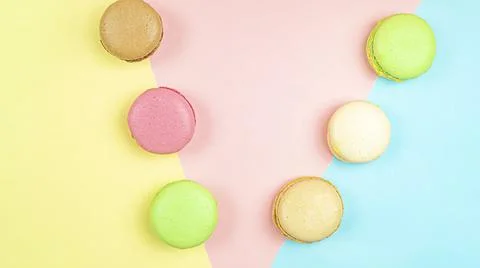 Multicolored macaroon cakes on colored bedding background with copy space Stock Photos
