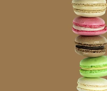 Multicolored Macaroon column on brown chocolate background Stock Photos