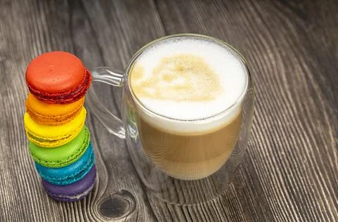 Multicolored macaroons and a transparent mug of cappuccino. The concept of fr Stock Photos