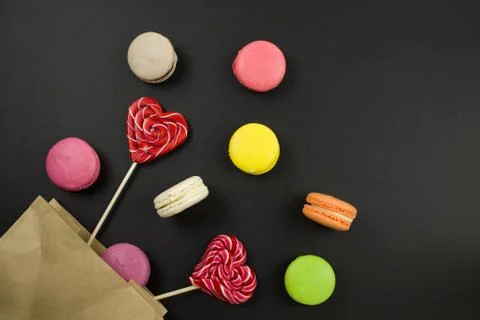 Multicolored macaroons on a black background, top view. apaper bag. 스톡 사진