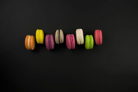 Multicolored macaroons on a black background, top view. Flat lay Stock Photos
