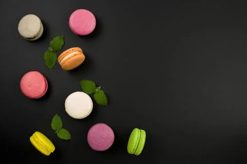 Multicolored macaroons on a black background, top view. Mint leaves. Flat lay 스톡 사진