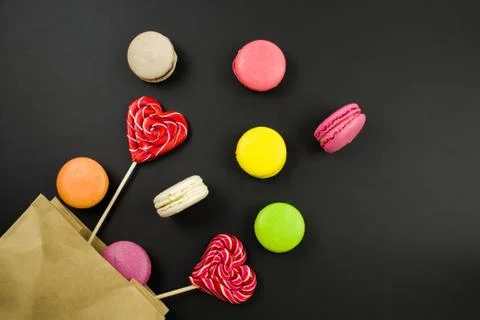 Multicolored macaroons on a black background, top view.paper bag. Stock-Fotos