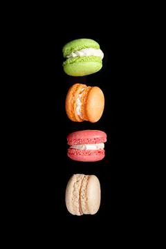 Multicolored macaroons isolated on black background falling or flying in moti Stock Photos