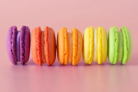 Multicolored macaroons in a row on a pink background Stock Photos