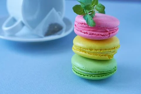 Multicolored macaroons with tea on blue background. Selective focus. Stock Photos