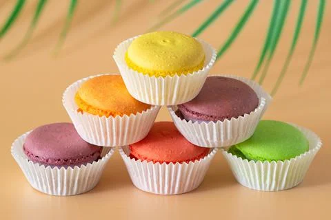Multicolored macaroons in white packaging are stacked in a pyramid Stock Photos