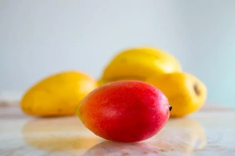 Multicolored mango fruit on the table. Selective focus on red mangoes. Stock Photos