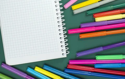 Multicolored markers or felt-tip pens and notepad on the green background. Stock Photos