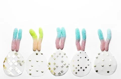 Multicolored marmalade in the shape of rabbit ears over paper eggs Stock Photos