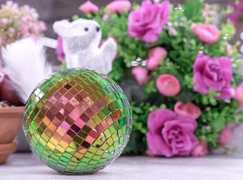 Multicolored mirror disco ball on a background of white squirrel and flowers. Stock Photos