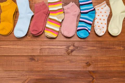 Multicolored new socks in different sizes stacked on a wooden background. clo Stock Photos