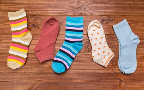 Multicolored new socks in different sizes stacked on a wooden background. clo Stock Photos