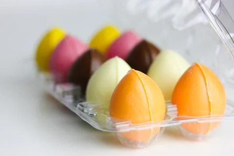 Multicolored orange pink Easter chocolate eggs in thermoplastic packaging Foto stock