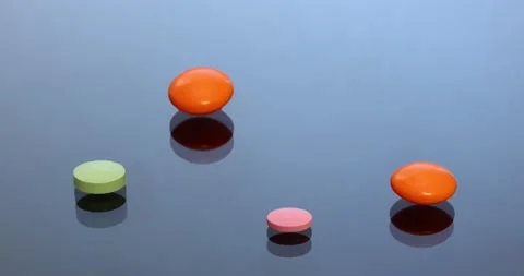 Multicolored oval and cylindrical tablets with shadow on blue glass. Stock Footage 146536544