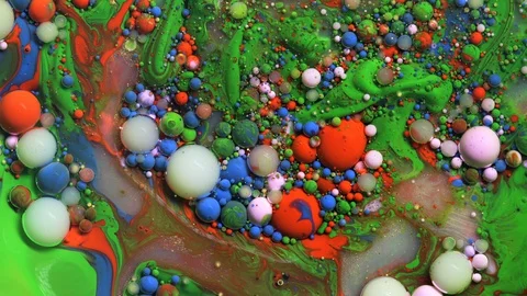 Multicolored paint bubbles on green surface, ink spheres drops and mixing Stock Footage 128763273