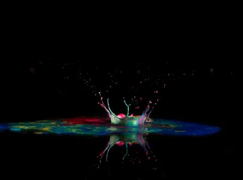 Multicolored paint drop crown abstract reflected on black background Stock Photos