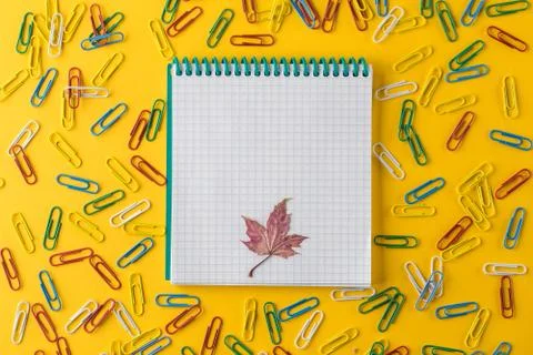 A multicolored paper clips and Notepad on a yellow background Stock Photos