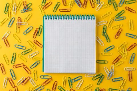 A multicolored paper clips and Notepad on a yellow background Stock Photos