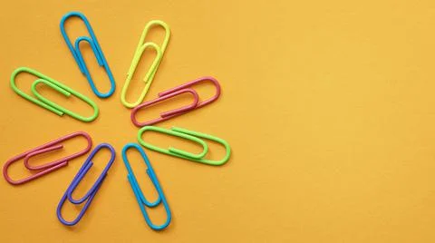 Multicolored paper clips in a circle in the form of a flower on the blank Ora Stock Photos