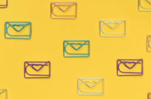 Multicolored paper clips in the form of a mail envelope with a heart on a yellow 스톡 사진