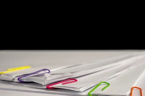 Multicolored paper clips on paperwork Stock Photos