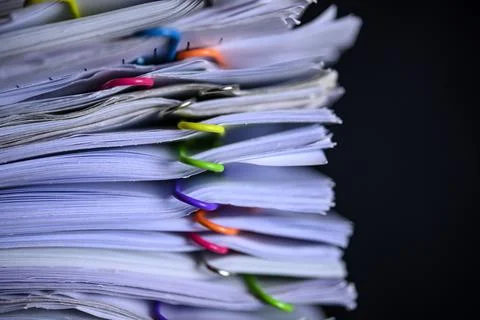 Multicolored paper clips on stack of paperwork Stock Photos