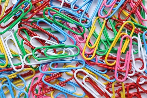 Multicolored paper clips on white background. Office paper clip. Stock Photos
