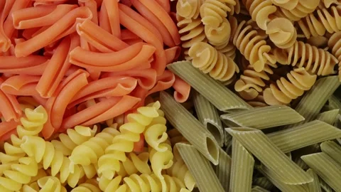Multicolored Pasta rotating in slow motion top view. Rotation of Colored spiral Stock Footage 141870445