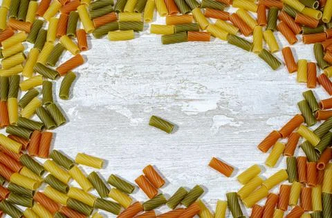 Multicolored pasta scattered on the kitchen table in the form of a frame Stock Photos