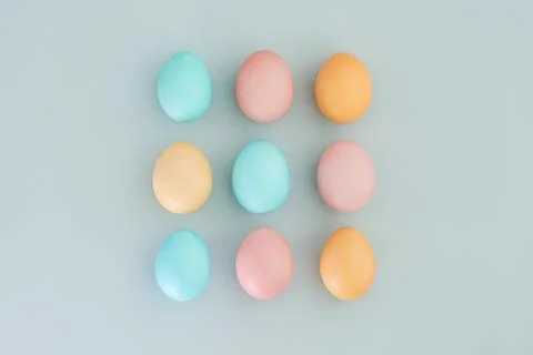 Multicolored pastel Easter eggs on a blue background. Top view, flat lay Stock Photos