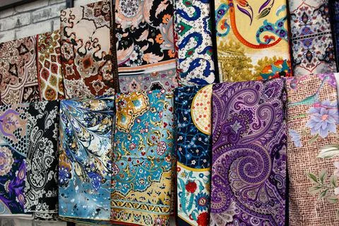 Multicolored patterned fabrics in a market. Full frame stacks of colored clot Stock Photos