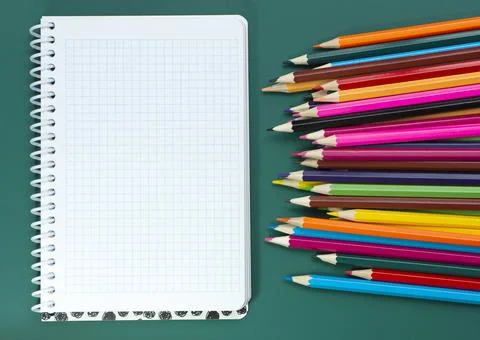 Multicolored pencils and a notebook on the table Stock Photos