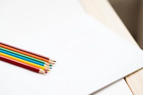Multicolored pencils lying on a white table Stock Photos