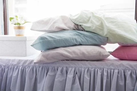 Multicolored pillows on the bed at the light window 스톡 사진